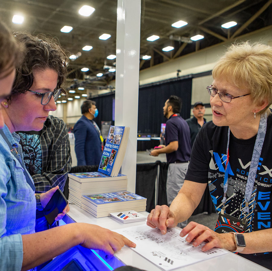 Volunteer assists attendee at Pit Admin booth at VEX Robotics World Championship