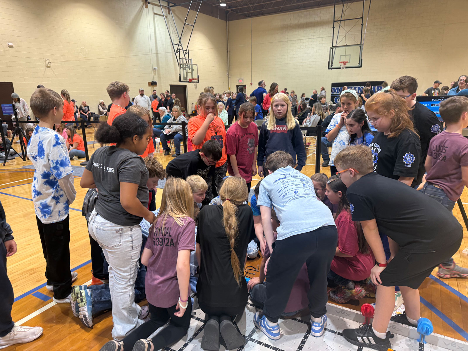 Participants gather to help a team fix a glitch at a VEX IQ Robotics Competition event