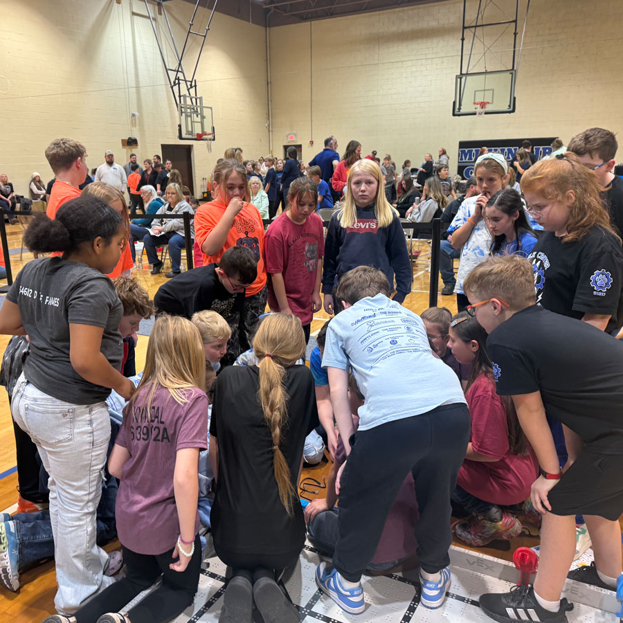 Participants gather to help a team fix a glitch at a VEX IQ Robotics Competition event